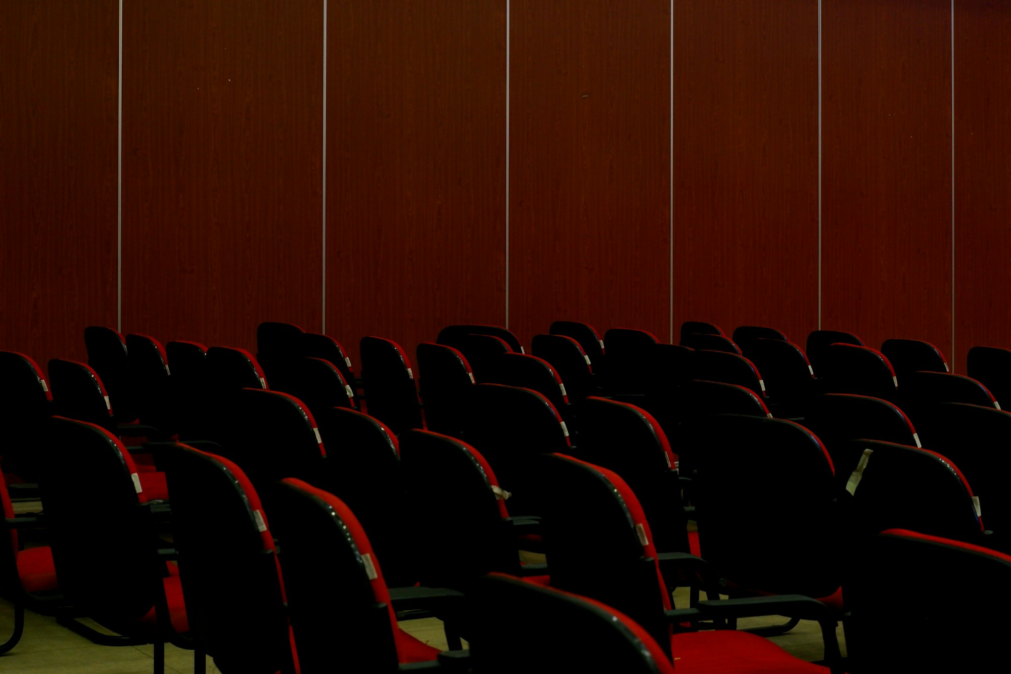 a row of red chairs in front of a wooden wall